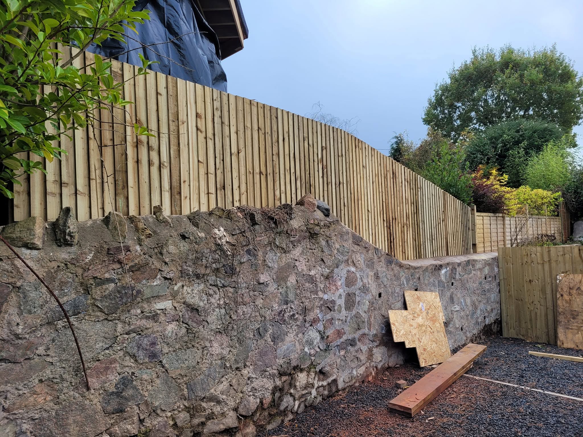 New featheredge fence built along the top of an old stone retaining wall