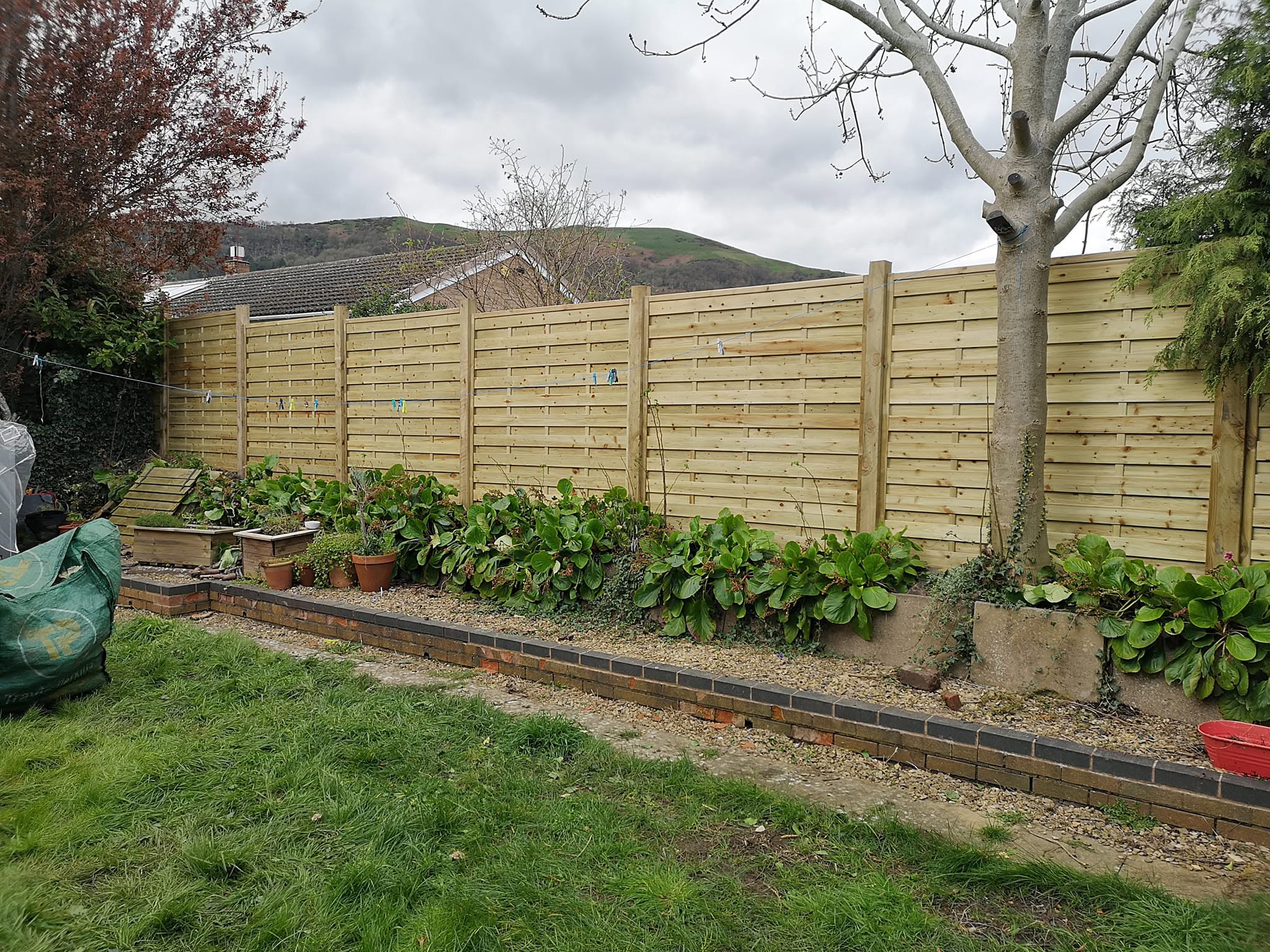 New horizontal slatted fence with hills rising behind