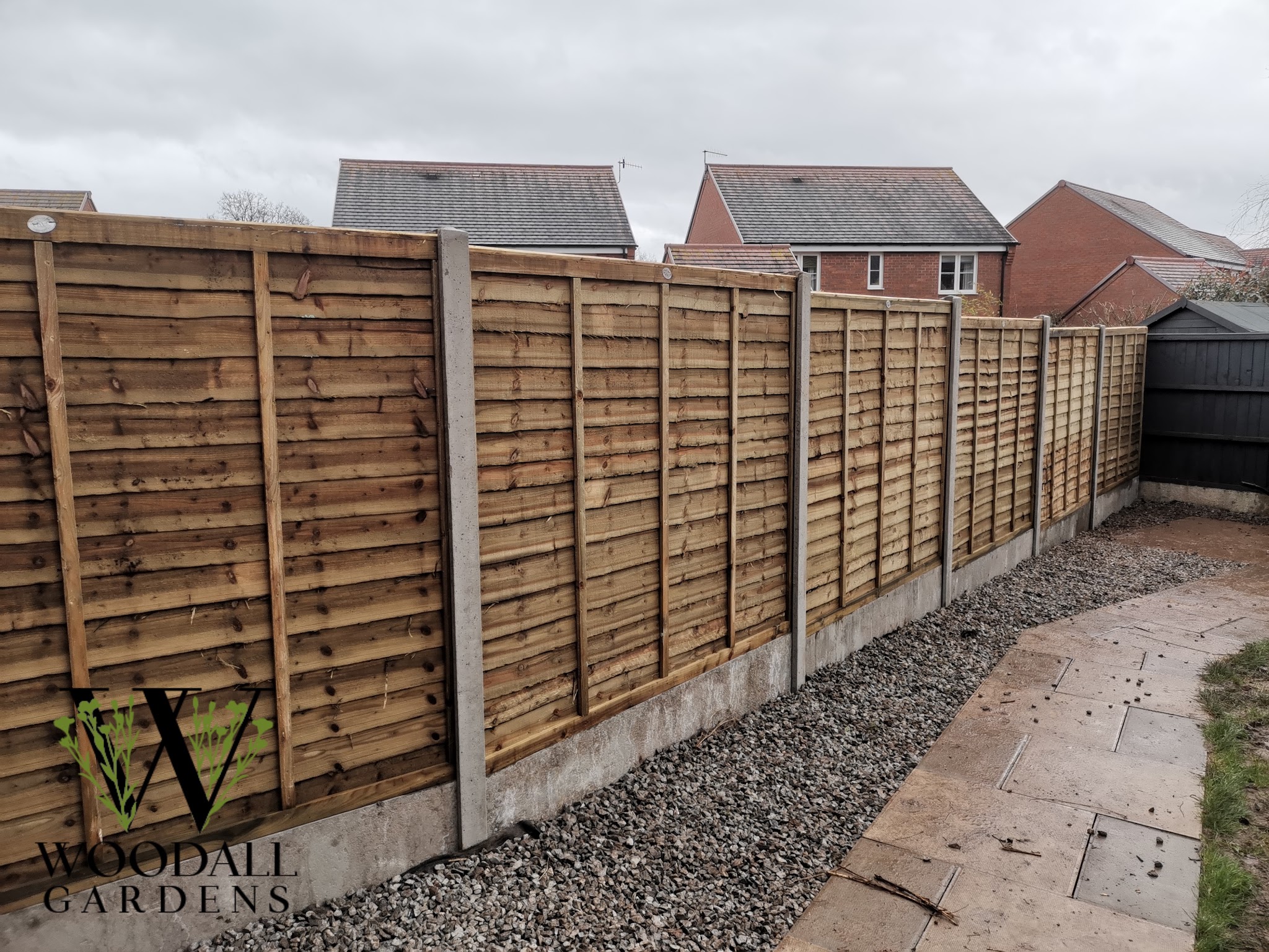 Lap panel fence on concrete posts beside a new path