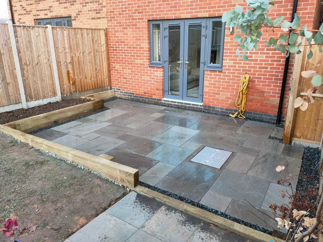 Grey slate patio with sleeper edging and a new fence