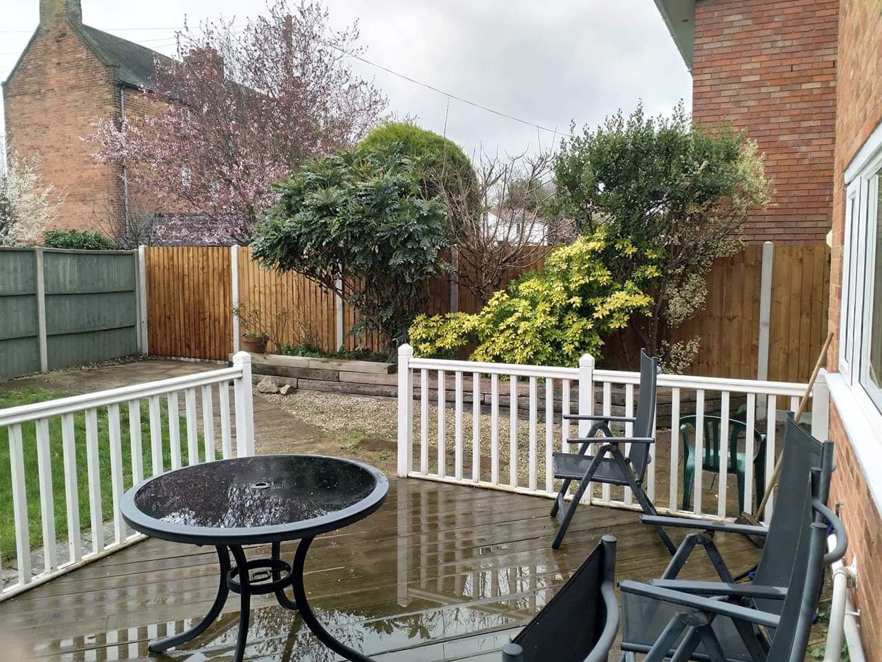 Decking with white balustrade and fencing behind