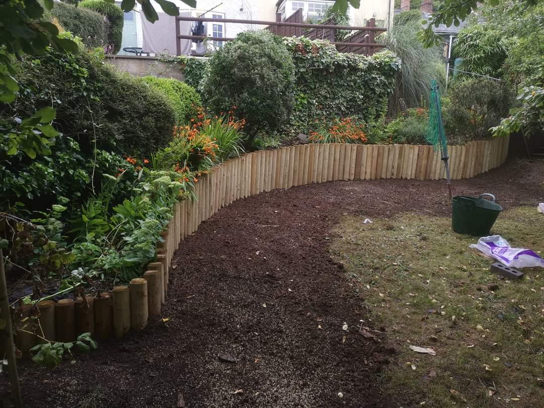 Curving log roll edging along a freshly dug border